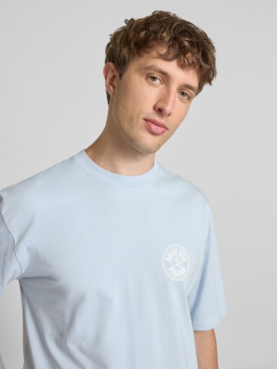 Männermodel trägt Oversized T-Shirt mit Label-Print von Pegador in Hellblau, Reine Baumwolle, Rundhalsausschnitt, Nahaufnahme Oberkörper.