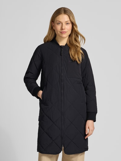 Modelka kobieca nosi czarną Steppjacke mit Zweiwege-Reißverschluss Modell 'YMAL2' od khujo, krój regular fit, długość do kolan, przód, zbliżenie na całość sylwetki. Szerokość w rozmiarze S: 50 cm, długość tyłu: 92 cm, szerokość ramion: 38 cm, długość rękawa: 60 cm.