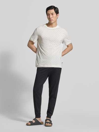 Männermodel trägt Sweatpants mit Logo-Muster und elastischem Bund von JOOP! Collection in Schwarz, Regular Fit, Ganzkörperansicht von vorne.