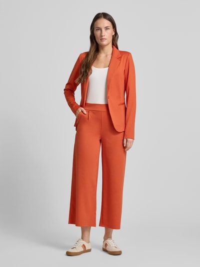 Vrouwenmodel draagt Wide Fit Stoffhose mit Viskose-Anteil Modell 'Kate' van ICHI in oranje, met elastische taille en wijde pijpen, Ganzkörperansicht von vorne.