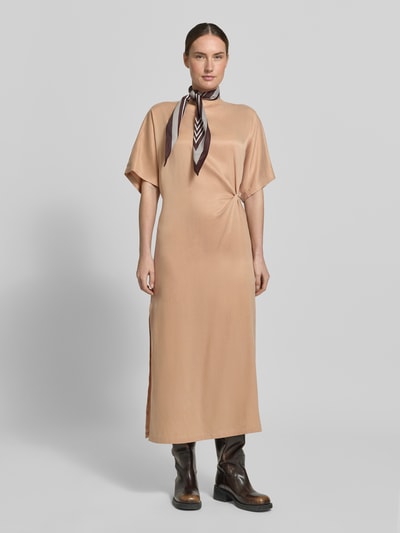 Frauenmodel trägt Midikleid mit Knotendetail Modell 'INDAH' von Drykorn aus Cupro-Baumwoll-Mix, Gerader-Schnitt, Rundhalsausschnitt, Seitenschlitz, beige Farbton, glatte Textur, Ganzkörperansicht von vorne. Brustweite bei Größe 36: 54 cm, Rückenlänge: 127 cm, Ärmellänge: 30 cm.