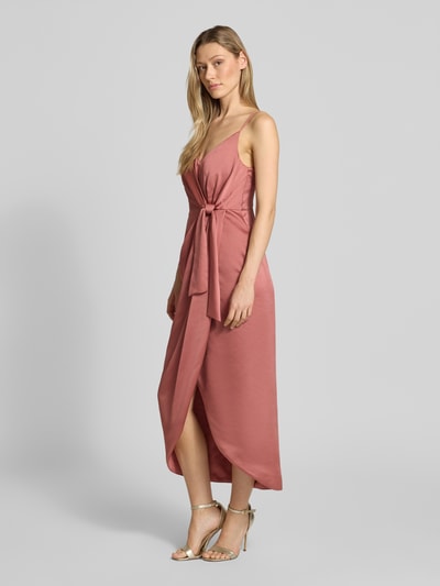 Frauenmodel trägt Regular Fit Midikleid mit verlängerter Rückseite von Jake*s Cocktail aus Satin in Wickel-Optik mit Spaghetti-Trägern, Nahtreißverschluss, Raffung, V-Ausschnitt, Altrosa-Farbton, Ganzkörperansicht von vorne. Rückenlänge bei Größe 36: 130 cm, Brustweite: 34 cm.
