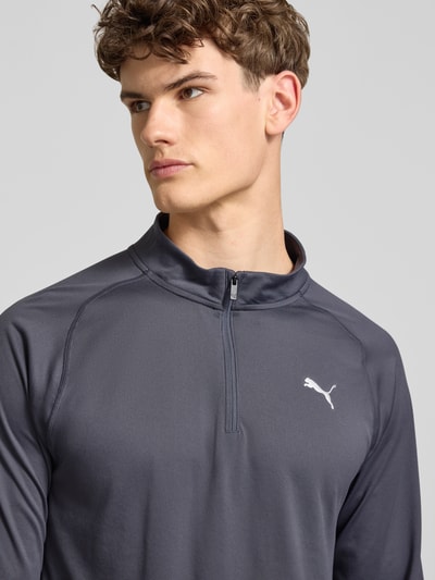 Männermodel trägt Langarmshirt mit Stehkragen und Reißverschluss von PUMA PERFORMANCE, Regular-Fit, Logo, dunkles Grau, Nahaufnahme Oberkörper. Rückenlänge bei Größe M: 71 cm.