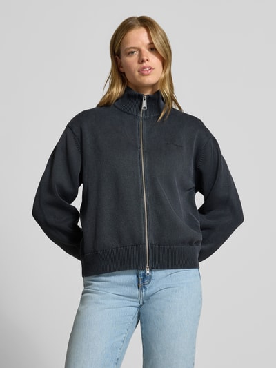 Frauenmodel trägt Cardigan mit Label-Stitching Modell 'Kori' von Carhartt Work In Progress in Dunkelblau, Zweiwege-Reißverschluss, Reine Baumwolle, Relaxed Fit, Stehkragen, Vorderansicht Ganzkörperansicht.
