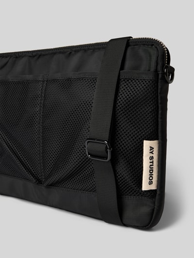 Produktfoto, schwarze Laptop-Tasche mit Logo-Detail von AY STUDIOS, Reißverschlussfach, Netz-Taschen, abnehmbarer Schulterriemen, rechteckige Form, glatte und Netztextur, 40x28x4 cm, 92 cm Schulterriemen.
