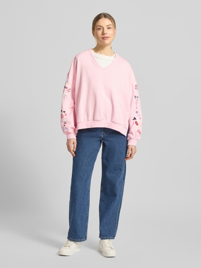 Vrouwenmodel draagt Oversized Fit Sweatshirt met V-hals van Smith and Soul, katoen-modal-mix, elastische boorden, lichtroze, blauwe jeans, witte sneakers, voorkantaanzicht van top tot teen.