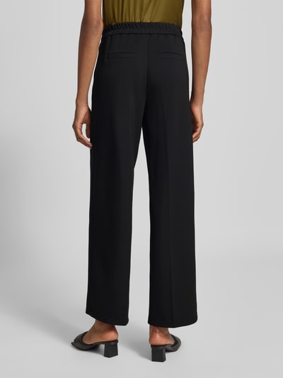 Männermodel trägt czarne, szerokie spodnie z mieszanki modalu Regular Fit Weite Hose aus Modal-Mix Modell 'BELLIS' von VERO MODA, widok całej sylwetki z tyłu, kontekst: damskie szerokie spodnie od VERO MODA.