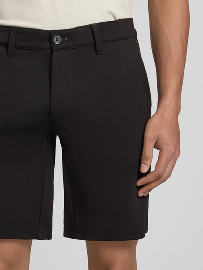 Männermodel trägt Regular Fit Bermudas aus Viskose-Mix Modell 'MARK' van Only & Sons in effen kleuren met steekzakken, labelapplicatie, riemlussen, knoop- en ritssluiting, geweven stretchstructuur, mix van viscose; detailaufnahme bovenbenen.