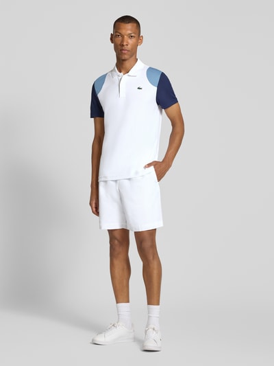 Männermodel trägt Regular Fit Sport-T-Shirt im Colorblock-Design von Lacoste in Weiß und Blau, Herren Sport-T-Shirt, Ganzkörperansicht von vorne.