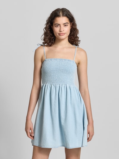 Frauenmodel trägt Damen Minikleid mit Smok-Detail von Noisy May aus Reine Baumwolle in Denim-Optik, A-Linie, Träger mit Schnürung, Ganzkörperansicht von vorne. Modell 'OREGON', Rückenlänge bei Größe S: 68 cm, Brustweite bei Größe S: 35 cm.