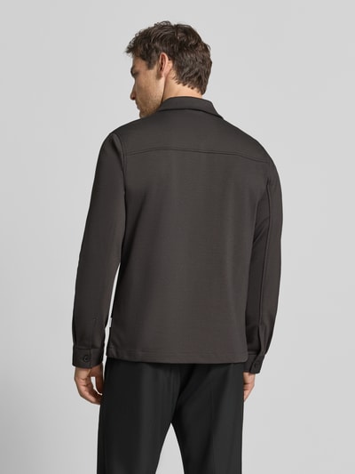 Męski model nosi Slim Fit Hemdjacke mit Viskose-Anteil von Lindbergh, elastyczna mieszanka materiałów, wykładany kołnierz, wpuszczane kieszenie, długość tyłu w rozmiarze M: 70 cm, widok całej sylwetki od tyłu.