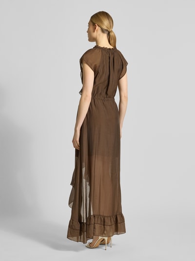 Modelka nosi Maxikleid aus Lyocell-Mix mit Volants Modell 'MAELYS' od Guess, brązowy, lekko przezroczysty, A-linia, widok całej sylwetki z tyłu. Szerokość w rozmiarze S: 40 cm, długość pleców: 143 cm.