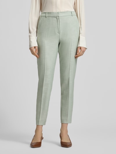 Vrouwenmodel draagt Slim Fit Stoffhose aus Viskose-Mix mit Bügelfalten van comma, lichtgroene kleur, rechte pijpen, broekzakken, elastische viscosemix, haak- en ritssluiting, biesplooien, maat 36, volledige lichaamsweergave van voren.