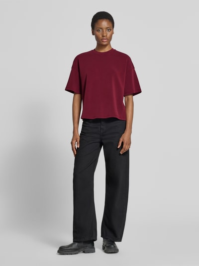 Frauenmodel trägt Oversized Sweatshirt aus Modal-Mix Modell ''TENNY'' von Selected in Dunkelrot zu schwarzer Hose, Ganzkörperansicht von vorne. Damen Sweatshirt von Selected.