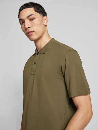 Männermodel trägt Regular Fit Poloshirt aus reiner Baumwolle Modell 'Core' von G-Star Raw in Oliv mit Polokragen und Label-Detail, Nahaufnahme Oberkörper.