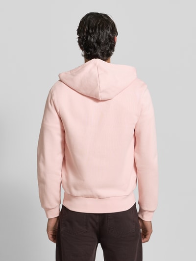 Männermodel trägt Regular Fit Sweatjacke aus Baumwoll-Mix von Lacoste in Rosa, Kapuze, Rippbündchen, unifarben, Ganzkörperansicht Rückansicht.