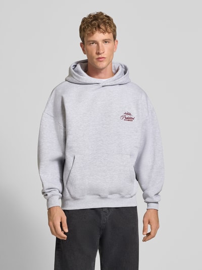 Männermodel trägt Relaxed Fit Hoodie aus Baumwoll-Mix mit Label-Stitching von PROHIBITED, hellgrau, Känguru-Tasche, Ganzkörperansicht von vorne.