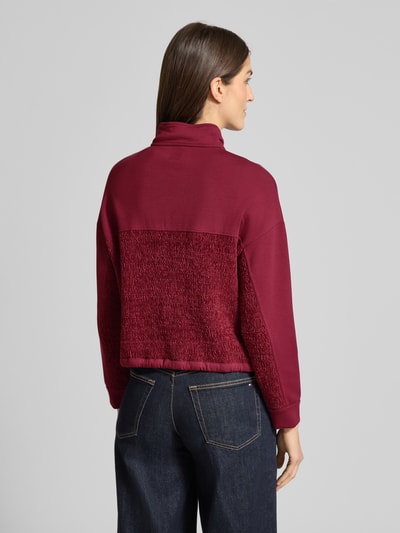 Frauenmodel trägt Regular Fit Sweatjacke mit Strickbesatz von Marc Cain in Bordeaux, Stehkragen, elastische Ärmel, Rückansicht, Baumwoll-Mix.