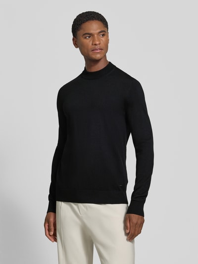 Männermodel trägt Regular Fit Pullover aus reiner Schurwolle Modell 'Davide' von JOOP! COLLECTION in Schwarz, Ganzkörperansicht von vorne.