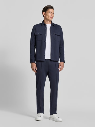 Männermodel trägt Straight Fit Hose mit Baumwoll-Anteil Modell 'Parker' von MCNEAL in Dunkelblau, glatte Struktur, Ganzkörperansicht von vorne. Herren Hose, Material-Mix mit Baumwoll-Anteil, Gesäßtasche, elastischer Bund, Innenbeinlänge 73 cm bei Größe M.