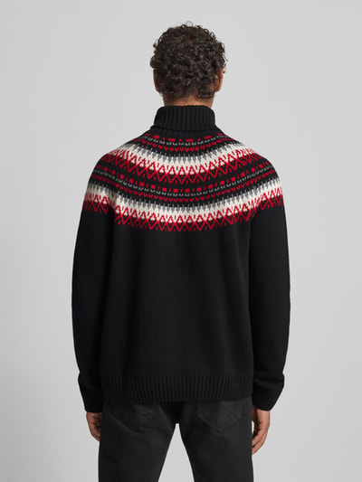 Männermodel trägt Strickpullover mit Rollkragen von Gant, schwarzer Woll-Baumwoll-Viskose-Mix, rote und weiße Muster, lockerer Schnitt, gerippte Abschlüsse, Rückenlänge 65 cm, Ärmellänge 84 cm, Ganzkörperansicht Rückansicht.