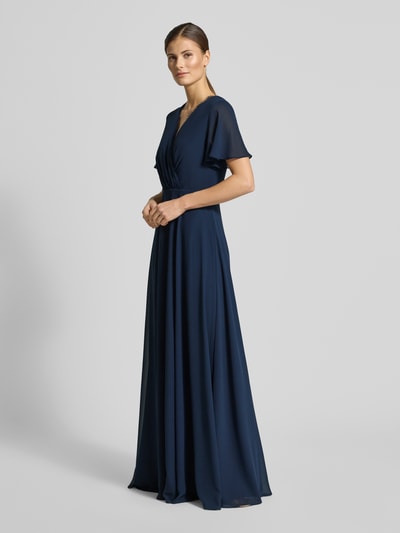 Frauenmodel trägt Damen Abendkleid mit Spitzenbesatz von Christian Berg Cocktail in Dunkelblau, taillierter Passform, V-Ausschnitt, Wickel-Optik, kurzärmelig, semitransparent, mit Raffungen, Ganzkörperansicht von vorne.