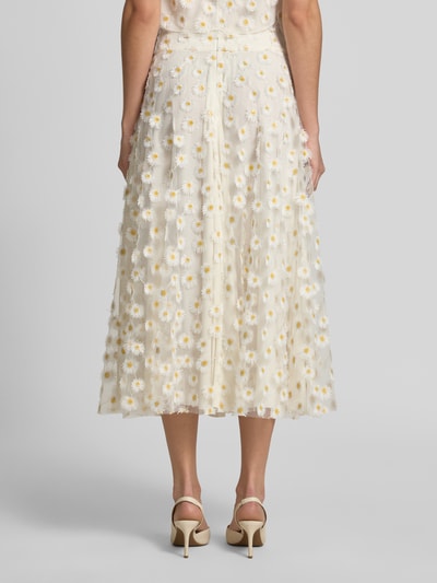 Frauenmodel trägt Midirock aus Tüll im Allover-Look von Luisa Cerano mit floralen Stitchings in Weiß und Gelb, A-Linie, Bundweite 52 cm, Ganzkörperansicht Rückansicht.