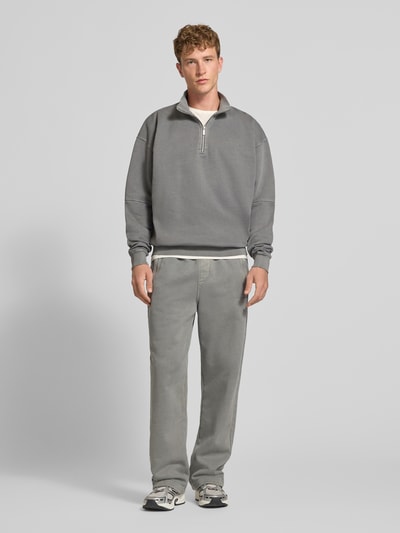 Männermodel trägt Loose Fit Sweatpants aus Baumwoll-Mix mit Label-Detail von PEGADOR, grauer Farbton, elastischer Bund, Eingrifftaschen, Ganzkörperansicht von vorne.