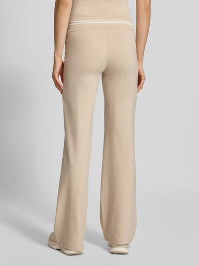 Frauenmodel trägt Flared Leggings mit elastischem Bund Modell 'Jasmin' von OH APRIL, beigefarbener Lyocell-Elasthan-Mix, Flared Cut, elastischer Bund, dezentes Label-Detail, Produktinfo Damen Leggings, Ganzkörperansicht Rückansicht.