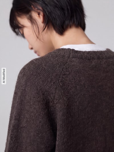 Frauenmodel trägt Oversized Strickjacke mit Woll-Anteil Modell 'BOOM' von VERO MODA in Dunkelbraun, strukturierte Oberfläche, Nahaufnahme Rückansicht, KI-modifiziertes Bild.