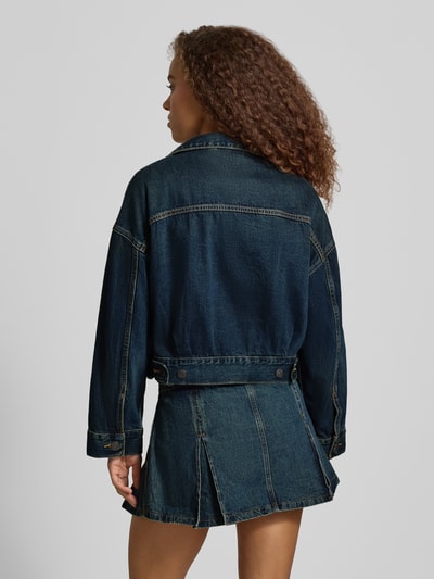 Frauenmodel trägt Jeansjacke mit Label-Detail Modell 'LOOSE CROP TRUCKER' von Levi's® 300 in dunklem Blau, Ganzkörperansicht Rückansicht.
