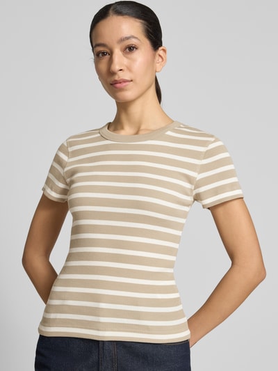 Modelka nosi damski t-shirt z bawełny, dopasowany krój, drobne prążkowanie, okrągły dekolt, model 'KOALE' od Drykorn, długość tyłu w rozmiarze S: 52 cm, beżowo-białe paski, ujęcie: całe ciało z przodu.
