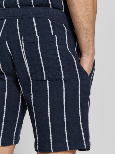 Mężczyzna nosi Shorts mit elastischem Bund und Tunnelzug od MCNEAL, ciemnogranatowy z białymi pionowymi paskami, czysta bawełna, krój regular fit, Szerokość w rozmiarze M: 42 cm, długość nogawki od wewnątrz: 20 cm, tekstura żakardowa, detal tylnej części, zbliżenie na górę nogawki