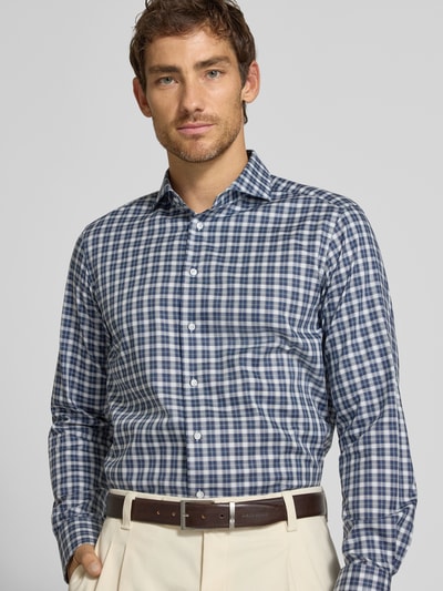 Männermodel trägt Regular Fit Business-Hemd aus Baumwolle von Christian Berg Men mit kariertem Muster in Weiß und Blau, Nahaufnahme Oberkörper. Reine Baumwolle, langärmlig, Haifischkragen.