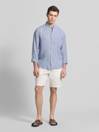 Męski model nosi Modern Fit koszulę casualową z czystego lnu Model 'Daniel' od Brax w biało-niebieskie paski, długość tyłu w rozmiarze M 76 cm, szerokość ramion w rozmiarze M 50 cm, długość rękawów w rozmiarze M 67 cm, kołnierzyk typu button down, listwa guzikowa, faktura lekko widoczna, całkowity widok z przodu.