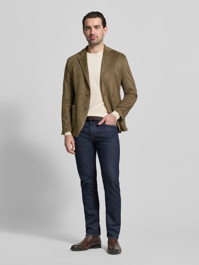 Männermodel trägt Regular Fit Sakko mit Reverskragen Modell 'Benito' von CINQUE in Oliv, kombiniert mit Jeans, Ganzkörperansicht von vorne. Elastischer Material-Mix, 2-Knopf-Sakko, aufgesetzte Taschen, Rückenlänge 73 cm, Schulterbreite 45 cm, Ärmellänge 65 cm.