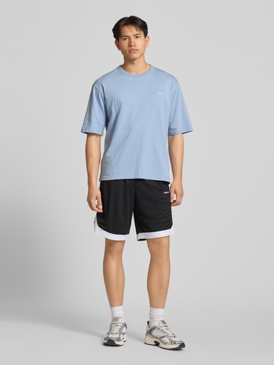 Männermodel trägt Relaxed Fit Shorts mit elastischem Bund von Pegador, schwarz-weiß, Logo-Stitching, Eingrifftaschen, Ganzkörperansicht von vorne