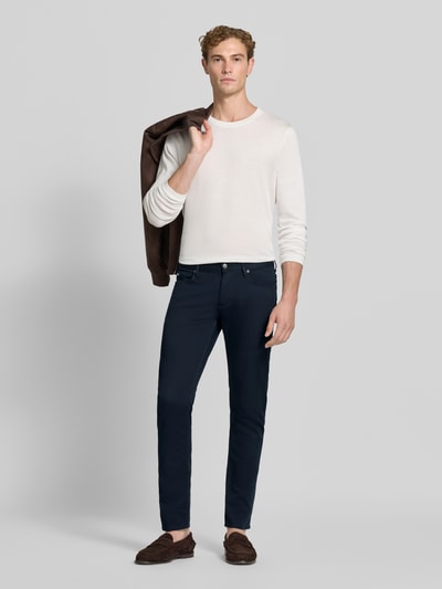 Männermodel trägt Slim Fit Jeans aus Baumwoll-Mix im 5-Pocket-Design von Emporio Armani, dunkles Blau, minimalistischer Look, Ganzkörperansicht von vorne.