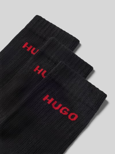 Produktfoto, zwarte sokken van katoenmix met rood HUGO-logo, geribde structuur, effen design, detailopname