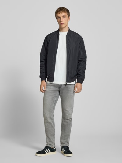 Männermodel trägt Slim Fit Jeans im Used-Look Modell 'Anbass' von Replay, grauer Farbton, 5-Pocket-Design, Ganzkörperansicht von vorne.