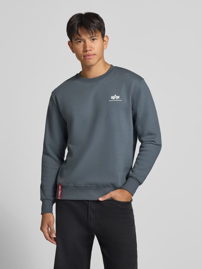 Männermodel trägt Sweatshirt mit Label-Details von Alpha Industries, gerader Schnitt, Baumwoll-Mix, Rundhalsausschnitt, graue Farbe, Ganzkörperansicht von vorne.