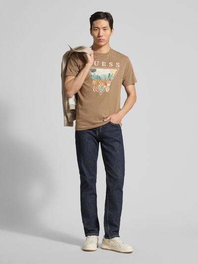 Mannelijk model draagt T-shirt met Motiv-Print model 'TIGER SPIRIT' van Guess in bruin met labelprint, rechte fit, katoen, voorkant volledige lichaamsweergave.