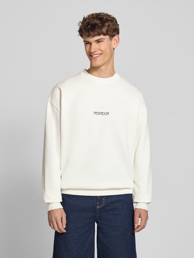 Męski model nosi Oversized Sweatshirt mit Logo-Print Modell 'Stavoren' od Pegador, bawełniana mieszanka, krój oversized fit, biały kolor, okrągły dekolt, elastyczne wykończenia, nadruk z logo, długość tyłu w rozmiarze M: 70 cm, długość rękawa w rozmiarze M: 65 cm, widok całej sylwetki z przodu.