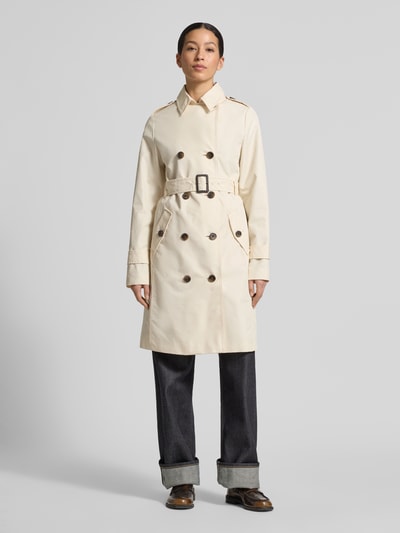 Modelka kobieca nosi Regular Fit Trenchcoat aus Baumwoll-Mix od s.Oliver RED LABEL w kolorze beżowym, długi rękaw, krój regular fit, dwurzędowe zapięcie, patki na ramionach, kieszenie z klapką, pasek, mieszanka bawełny, widok całej sylwetki z przodu.