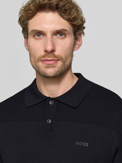 Männermodel trägt Relaxed Fit Poloshirt mit Woll-Anteil Modell 'KN_Momentum-X PL' von BOSS Green in Schwarz, Nahaufnahme Oberkörper.