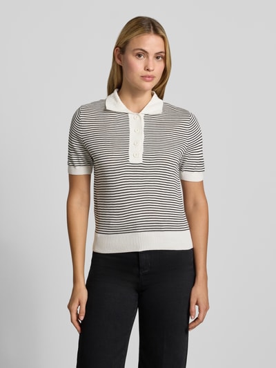 Frauenmodel trägt Poloshirt mit gerippten Abschlüssen von MANGO in Weiß-Schwarz mit feinen Streifen, gerade Passform, Polokragen, Halbarm, angenehme Strickstruktur, Ganzkörperansicht von vorne.