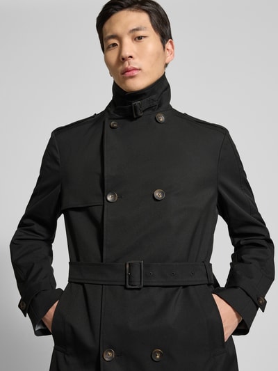 Męski model nosi Regular Fit Trenchcoat mit Reverskragen Modell 'Aberdeen' od CINQUE, czarny, podwójny rząd guzików, odpinany pasek, zbliżenie górnej części ciała. Szerokość w rozmiarze 50: 45 cm, długość pleców: 97 cm, szerokość ramion: 44 cm, długość rękawa: 66 cm.