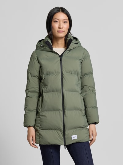 Modelka nosi Regular Fit płaszcz w z efektem pikowania z naszywką z logo khujo Model 'TANARE', kolor oliwkowy, zamek błyskawiczny dwustronny, Długość tyłu w rozmiarze S: 82 cm, szerokość ramion w rozmiarze S: 47 cm, szerokość w rozmiarze S: 47 cm, długość rękawów w rozmiarze S: 59 cm; widok całej sylwetki z przodu.