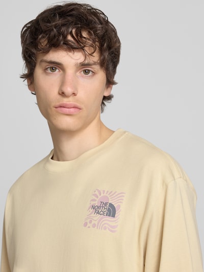Männermodel trägt Oversized T-Shirt mit Logo-Print von The North Face in Beige aus reiner Baumwolle, Nahaufnahme Oberkörper.