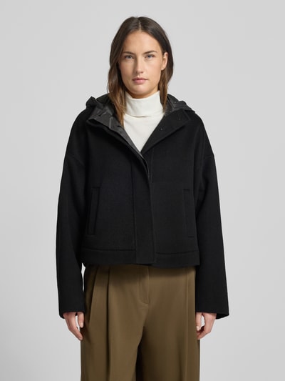 Vrouwenmodel draagt Jacke mit Kapuze van Marc Cain, zwart, puur katoen, regular fit, capuchon, steekzakken, ritssluiting, Ganzkörperaanzicht van voren. Ruglengte maat 36: 57 cm, schouderbreedte: 66 cm, borstwijdte: 58 cm, mouwlengte: 50 cm.